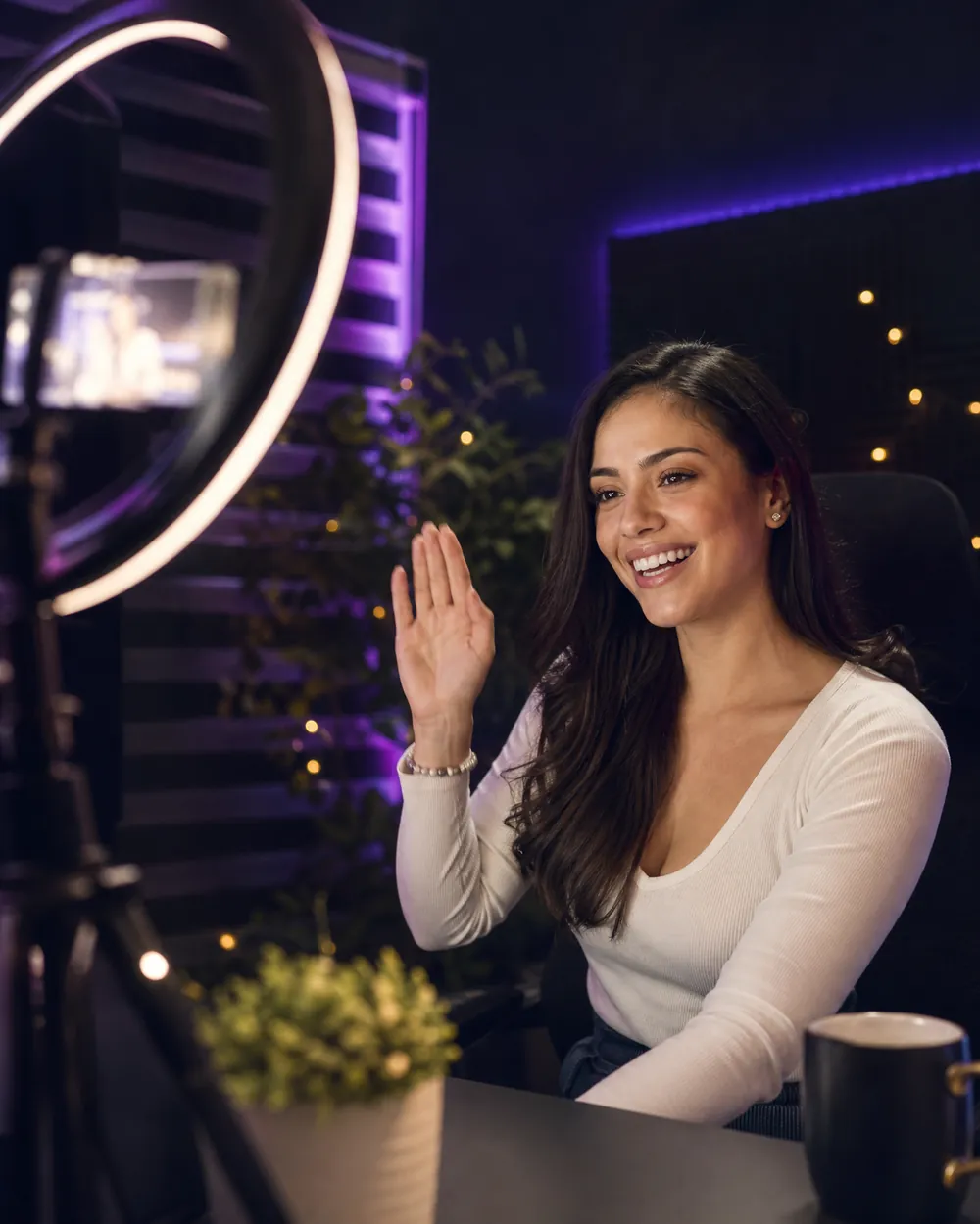 A smiling creator waves to her audience while streaming LIVE from her home studio